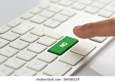 Computer Keyboard Concept: Hand pushing green NO keyboard button