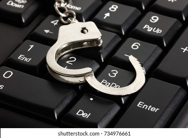 computer keyboard and handcuffs, crime computers technology isolated on white background.