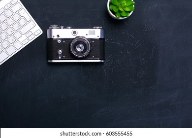 Computer keyboard, mouse and camera lie on a black table