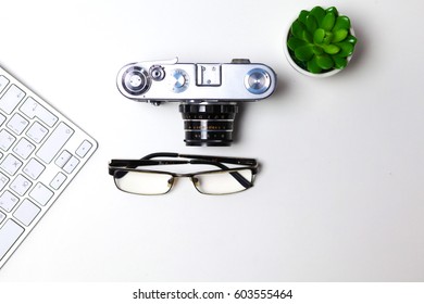 Computer keyboard, mouse and camera lie on a white table