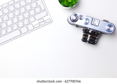 Computer keyboard, mouse and camera lie on table.