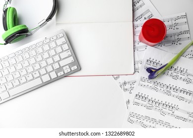 Computer keyboard, notebook and music sheets on table