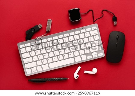 Computer keyboard with pen and different modern devices on red background. Top view