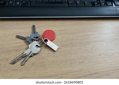 Computer keyboard surrounded by security devices: metal key, red key fob, usb drive indicating digital access and protection