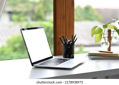 Computer Laptop With Empty Screen, Pencil Holder And Houseplant On White Office Desk