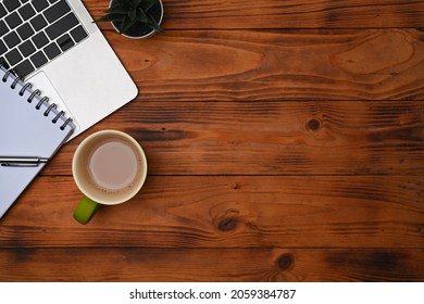 Computer laptop, notebook and coffee cup on wooden desk.