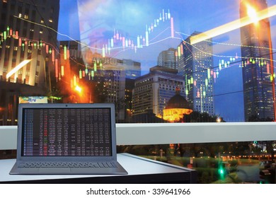 computer laptop with stock chart on screen at the window of city view