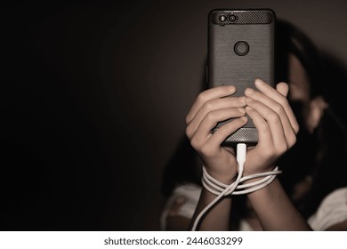 Computer, media, game, network, digital, technology, gadget  and  internet addiction. Young beautiful girl with tied hands using smartphone at night. Copy space for design. Horizontal image.