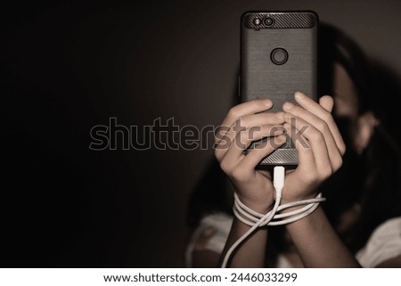 Computer, media, game, network, digital, technology, gadget  and  internet addiction. Young beautiful girl with tied hands using smartphone at night. Copy space for design. Horizontal image.