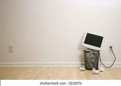 Computer Monitor In Trash Can Surrounded By Crumpled Up Paper.