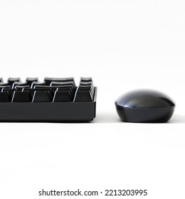 Computer Mouse And A Fragment Of A Black Mechanical Gaming Computer Keyboard On A White Background. Wireless Input Devices For Gadgets And Computer. Copy Space. Side View. Close-up