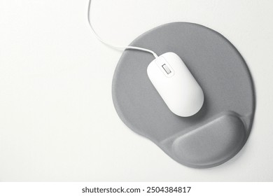 Computer mouse and mousepad with armrest on white table, top view. Space for text
