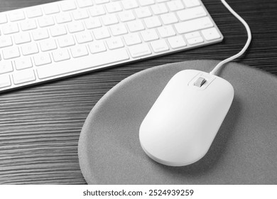 Computer mouse, mousepad and keyboard on black wooden table