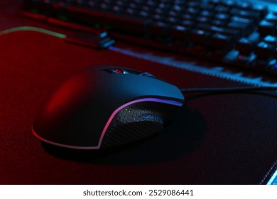 Computer mouse and mousepad on table in neon lights, closeup