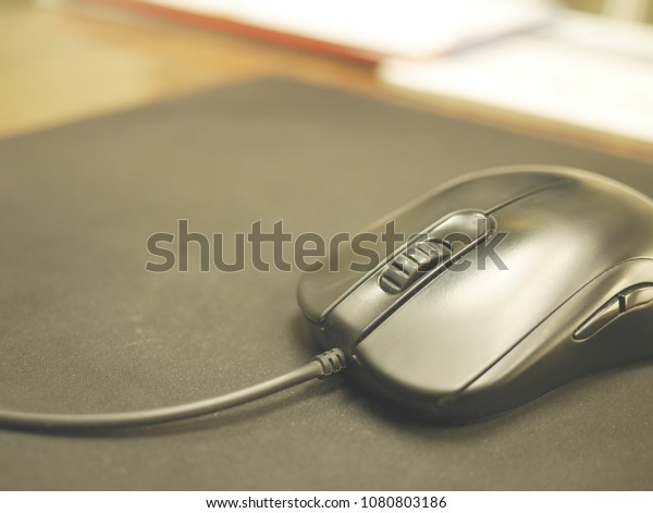 computer mouse on black mousepad on table\
in office with blurred background and copy\
space.