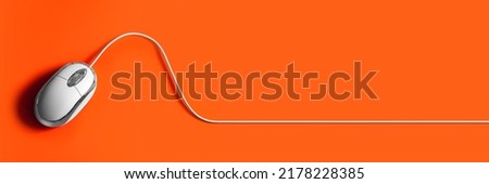 Computer mouse on an orange background. Mouse with cable. Background for web design.