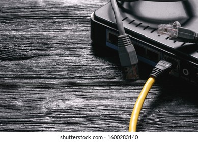 Computer network laying concept. Utp cable, net switch and connectors closeup on black wooden table background.