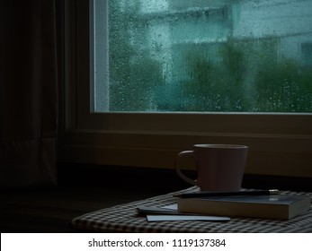 computer notebook next to a cup coffee on rainy day window background