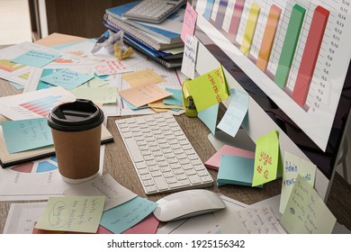 Computer, notes and office stationery in mess on desk. Overwhelmed with work