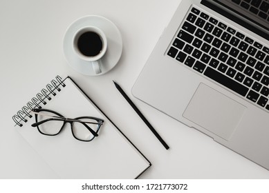 A Computer On The Desk. Notebook For Notes And Pencil And Glasses. Classic Coffee On A White Background.