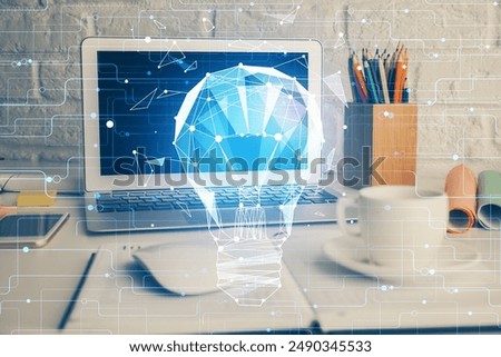 Computer on desktop in office with bulb icon hologram. Double exposure. Concept of idea.