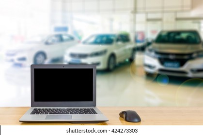 Computer On The Table, Blur Image Of Inside Car Dealership As Background.