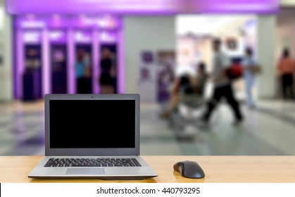 Computer on the table, blur image of people stand at ATM machine as background.