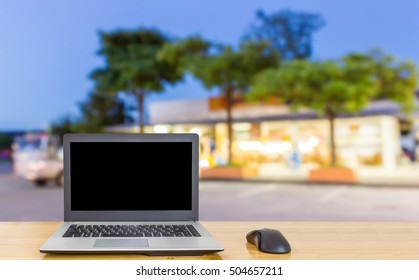 Computer on the table, blur image of restaurant in twilight as background.