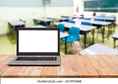 Computer on the table, blur image of empty classroom as background.