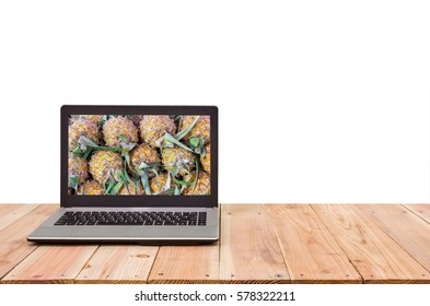 Computer on the table, pineapples on screen. 