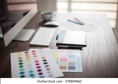 Computer, Pen Tablet, Color Swatches And Sketches On A Designer's Workspace With A Very Shallow Depth Of Field