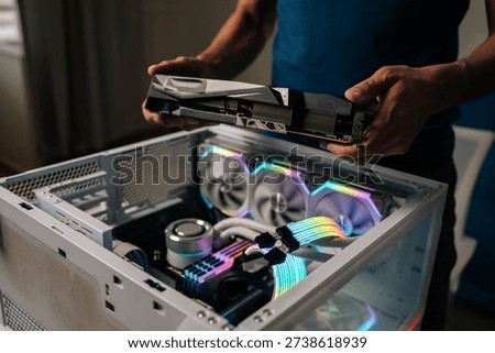 Computer professional inserting high-performance graphics card into custom gaming pc, illuminating interior with vibrant RGB lighting for enhanced visual experience. Concept of service, maintenance PC