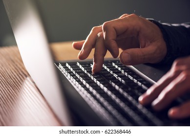 Computer programmer and hacker hands typing laptop keyboard, close up low key with selective focus