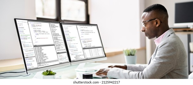 Computer Programmer Writing Program Code On Computer In Office