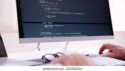 Computer Programmer Writing Program Code On Computer In Office