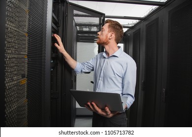 Computer programming. Confident IT technician examining server closet while carrying laptop - Powered by Shutterstock - Get 15% off with code: PIKWIZARD15