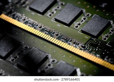 Computer RAM (Random Access Memory) memory module. Details of the gold contacts that fit into the motherboard and black flash memory chips soldered onto the green printed circuit board (PCB).