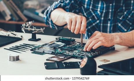 Computer repair shop. Engineer performing laptop maintenance. Hardware developer fixing electronic components. PC technology