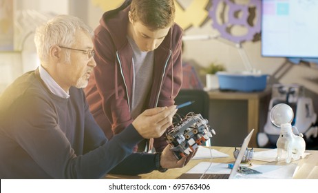 In Computer Science Class Teacher Examines Programed Robot Engineered By His Student For School Project.