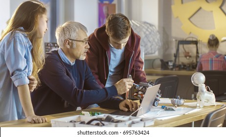 In Computer Science Class Teacher Examines Programed Robot Made By Girl And Boy.