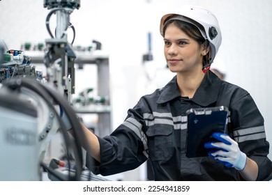 Computer science development engineer working on robotic arm connection and control using tablet software. Woman in industry 4.0 robotic engineering workshop in electronic futuristic technology center
