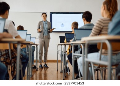 Computer science teacher giving a lecture to her high school students in the classroom.