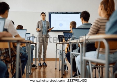 Computer science teacher giving a lecture to her high school students in the classroom.