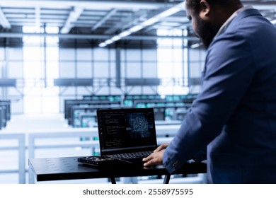 Computer scientist in data center using laptop to visualize artificial intelligence neural networks made up of interconnected nodes. African american man oversees AI systems processing information