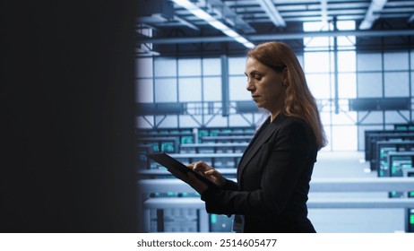 Computer scientist doing checkup, inputting data on tablet of needed fixes in server hub. Woman working in data center housing advanced data storage infrastructure supporting IT workloads, camera A
