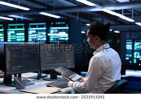 Computer scientist doing yearly checkup to prolong data center electronics life span and avoid downtime. IT staff member in server room monitoring server infrastructure components using tablet