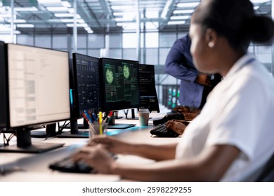 Computer scientist reconfiguring server farm to optimize it for data processing requirements of customers. African american woman working to ensure data center equipment operates efficiently