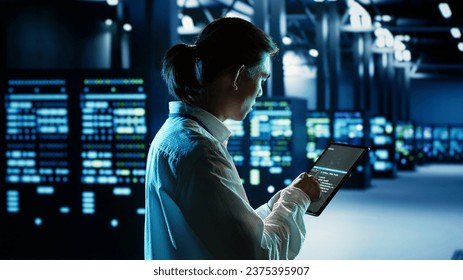 Computer scientist running code and programming on laptop, troubleshooting and upgrading server room equipment designed to accommodate mainframes, networking systems and storage arrays