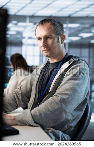 Computer scientist in server farm ensuring compliance with industry standards and regulatory requirements. Data center worker using PC, conducting security audits to protect against cyberthreats