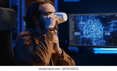 Computer scientist updating artificial intelligence neural networks, drinking coffee and writing code scripts in personal office. IT expert enjoying hot beverage while running AI simulations, camera A